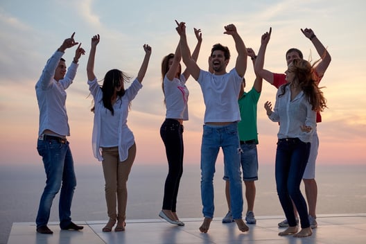 group of happy young people dancing and have fun on party in modern home bacony with sunset and ocean in background.jpeg
